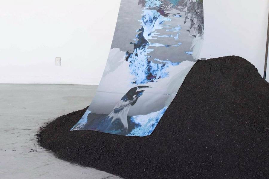 Grey and blue digital print hanging over a pile of soil.